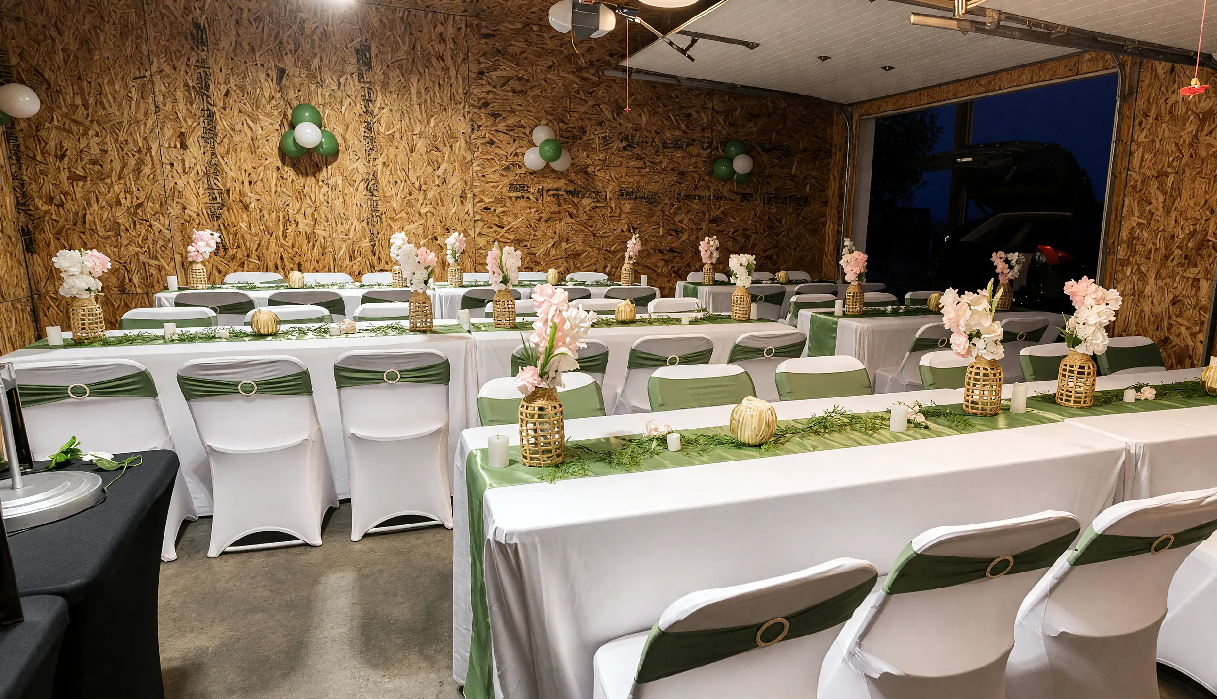 Event hall set by Ponnus Caters & Events with white table covers, green runners and flower centrepieces